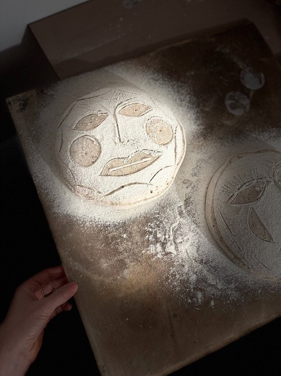Bemehlte Teiglinge mit eingeschnittenen Gesichtern im Sonnenlicht